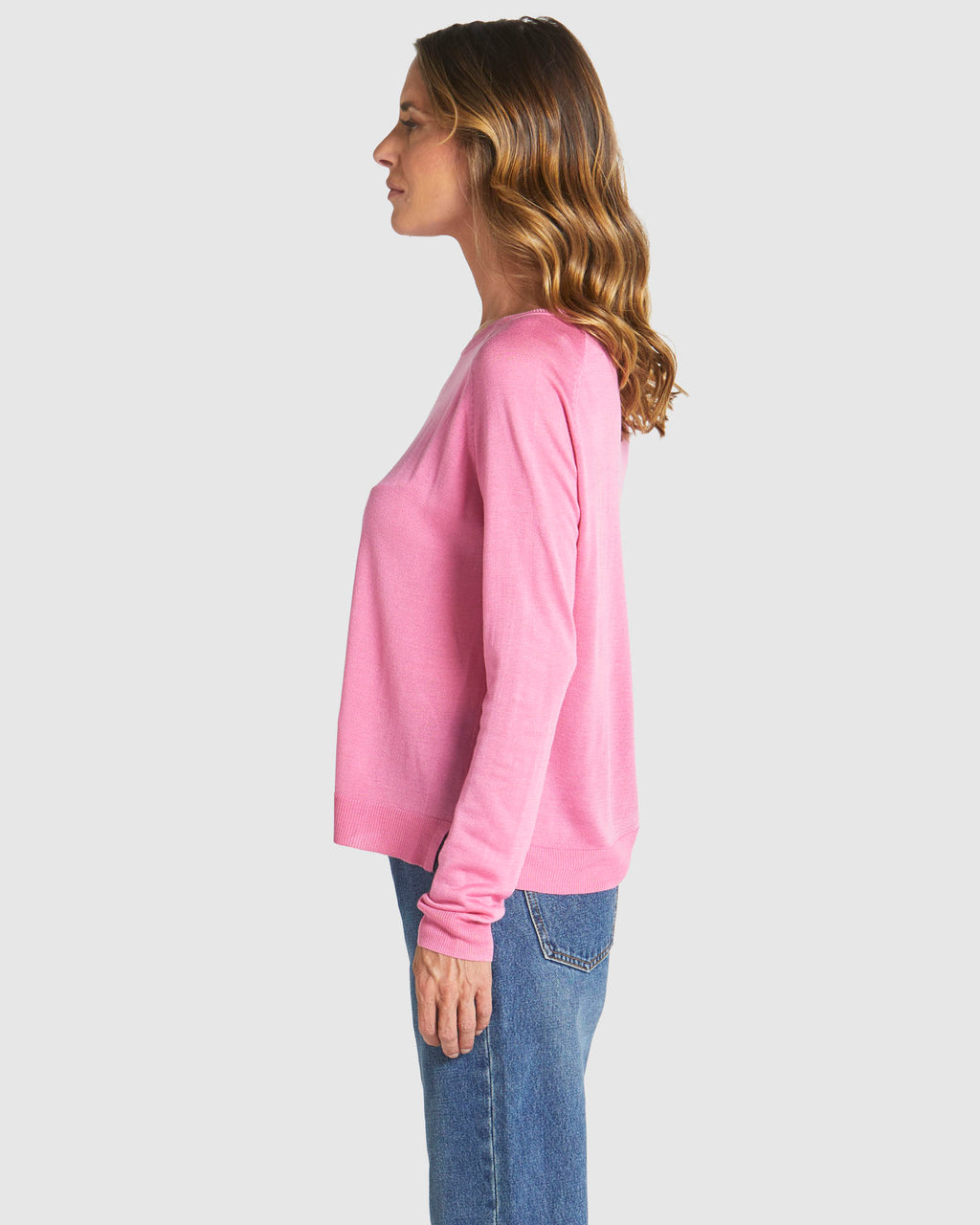 Woman wearing a pink long-sleeve top and blue jeans on a white background
Reminiscent Knit Pink