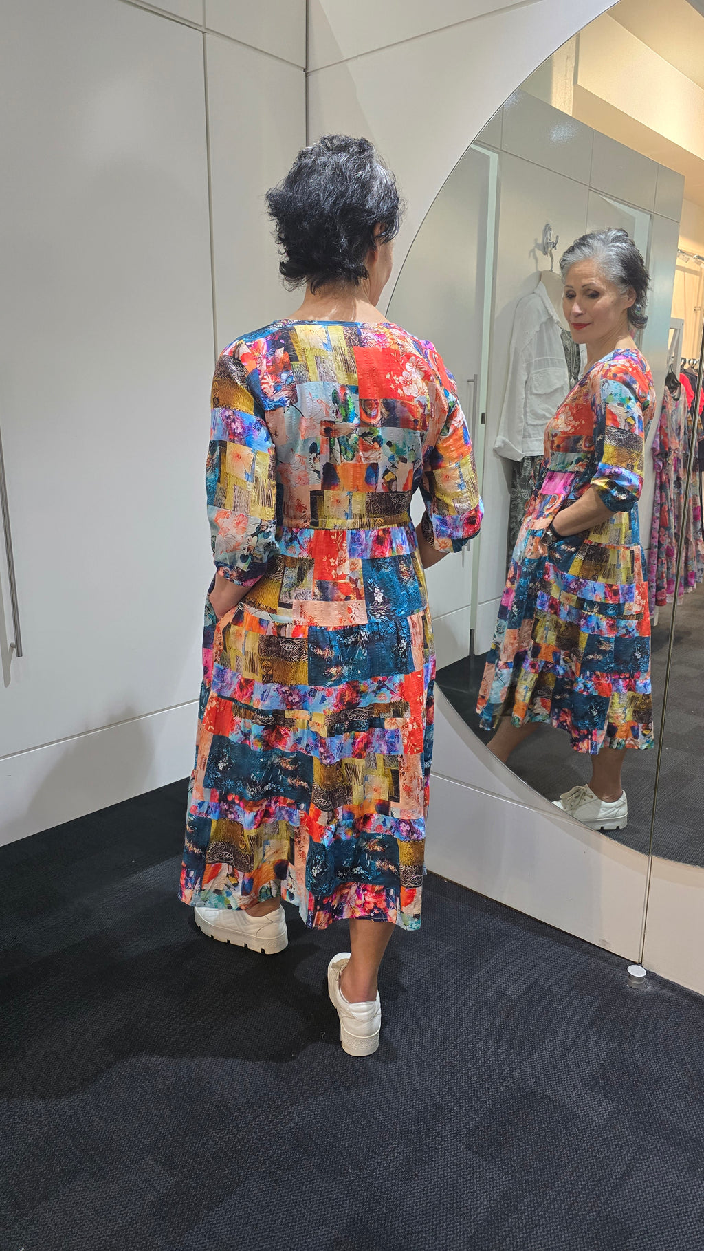 Woman wearing a colorful dress standing in front of a mirror. Tie Front Dress Turquoise