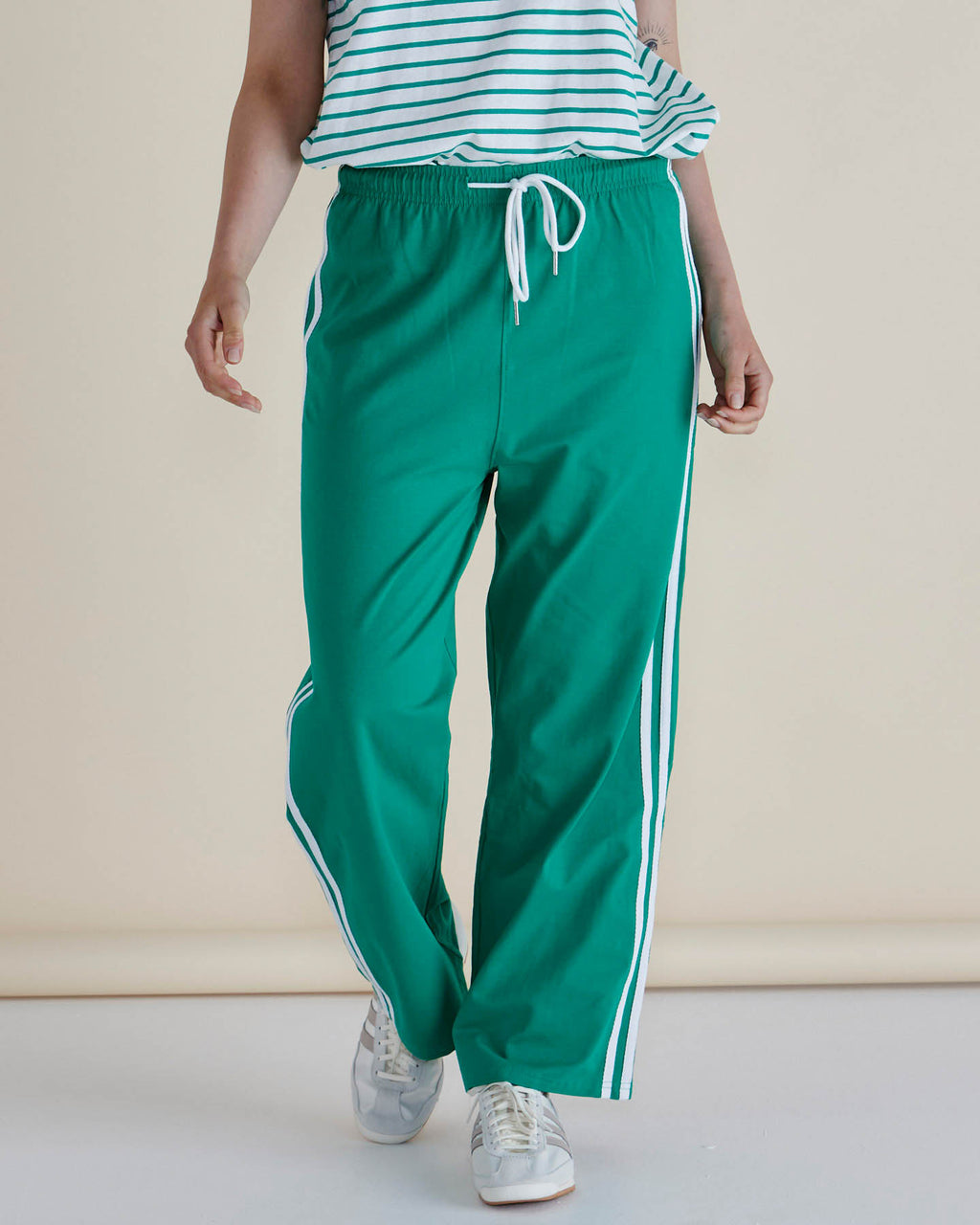 Woman wearing a striped shirt and green pants with white stripes on a plain background
Nikki Relax Cotton Jogger Green