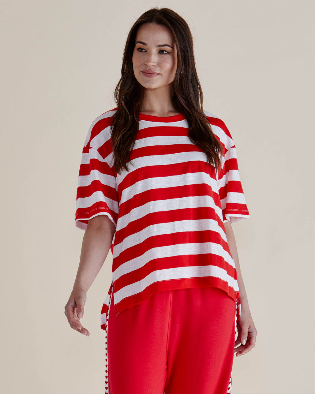 Woman wearing a red and white striped shirt and red pants against a beige background
