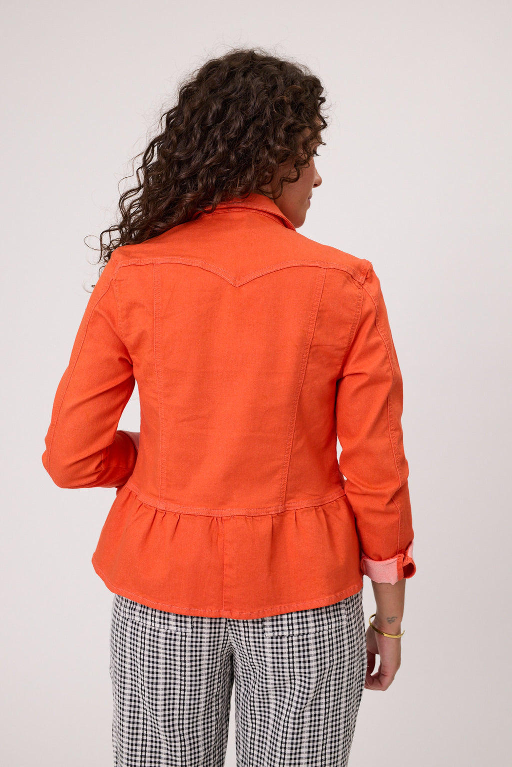 Woman wearing an orange jacket in front of a scenic backdrop