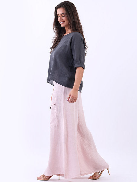 Woman wearing a gray top and light pink wide-leg pants on a white background