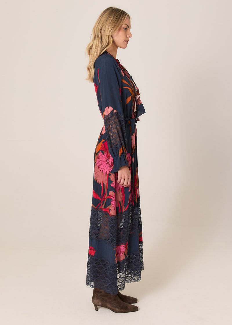Woman wearing a long, dark blue floral dress on a plain background