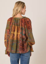 Woman wearing a patterned blouse with long sleeves and blue jeans on a beige background
Bohemian Top Nouveau Floral Green