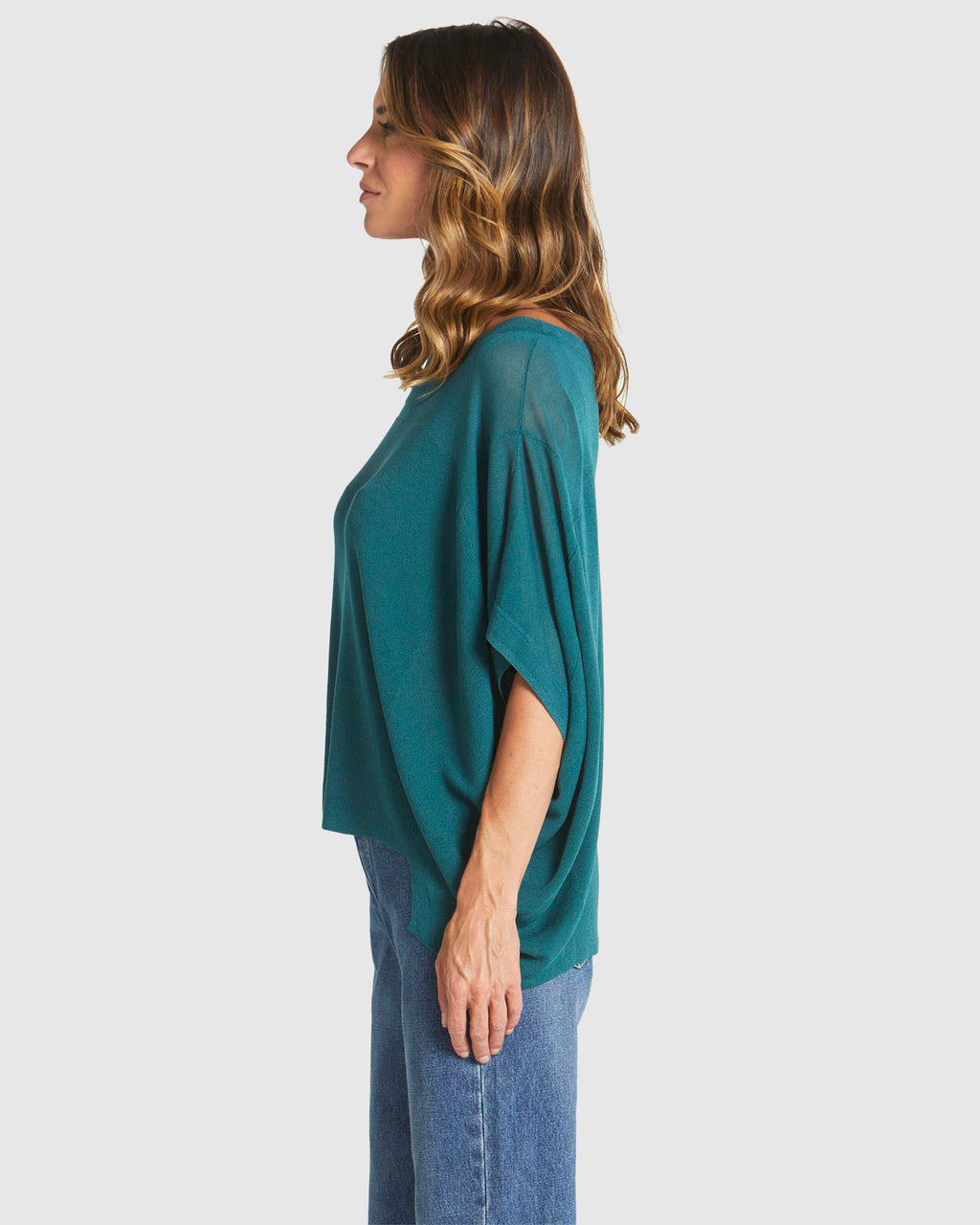 Woman wearing a teal poncho and blue jeans on a white background
Irises Knit Teal