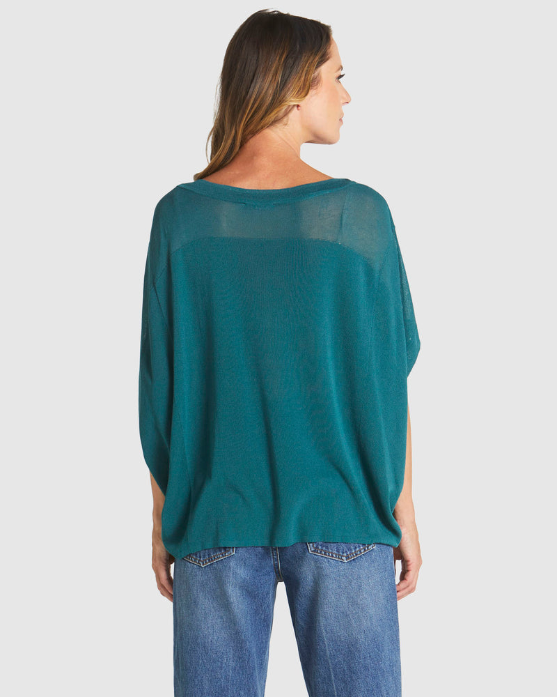 Woman wearing a teal oversized shirt and blue jeans on a white background
Irises Knit Teal