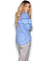 Woman wearing a blue ruffled blouse and gray pants on a white background
Frill Tunic Denim Blue