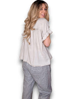 Woman wearing a light-colored blouse and gray pants on a white background
Eyelet Top Pale Beige