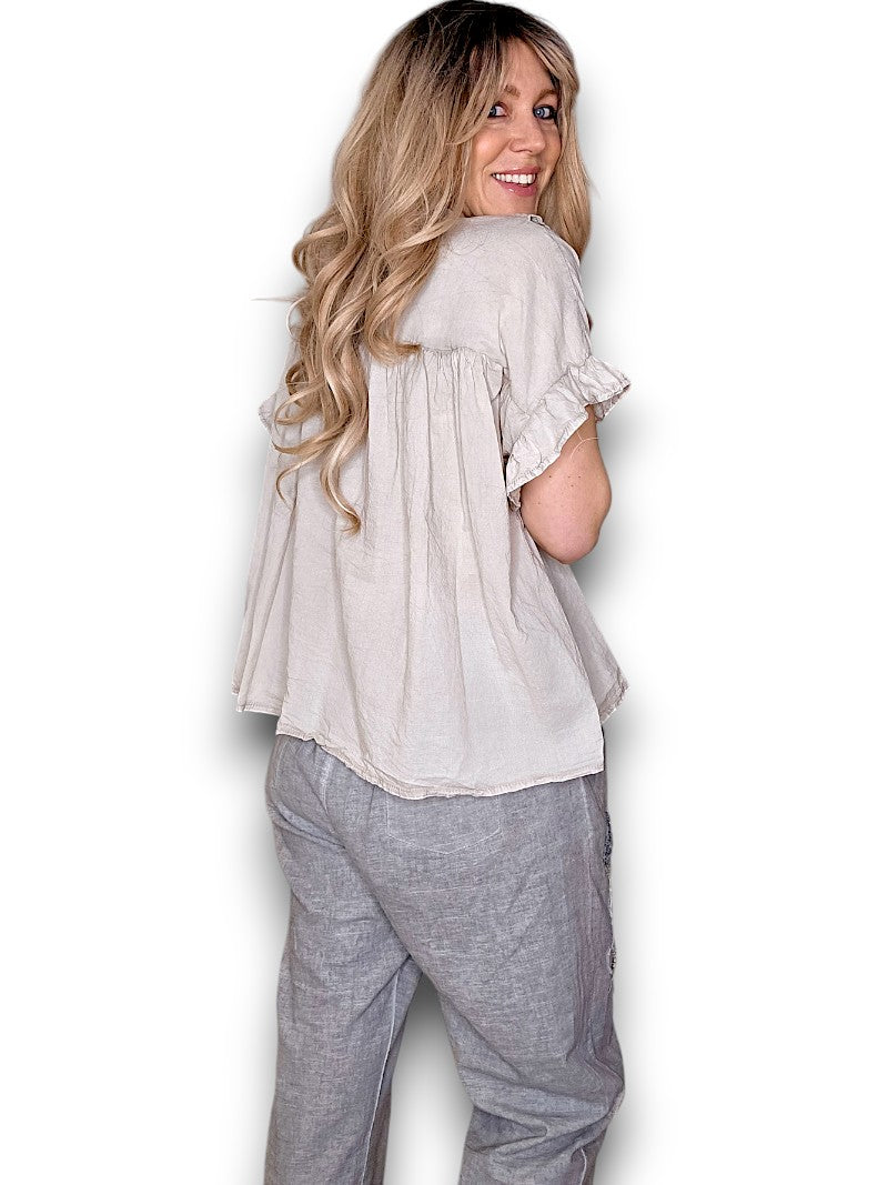Woman wearing a light-colored blouse and gray pants on a white background
Eyelet Top Pale Beige