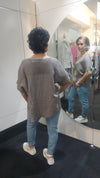 Person wearing a Taupe Top and blue jeans standing in front of a mirror.