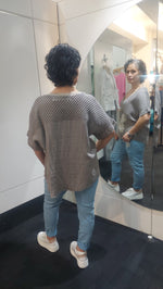 Person wearing a Taupe Top and blue jeans standing in front of a mirror.