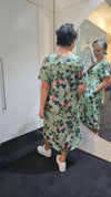 Woman wearing a floral dress standing in front of a mirror. Pleat Front Dress Green