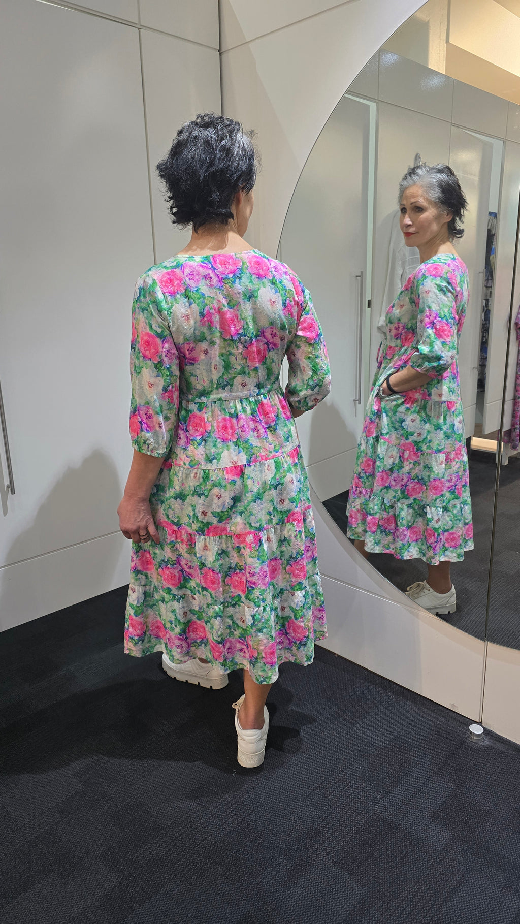 Person wearing a floral dress standing in front of a mirror. Tie Front Dress Green