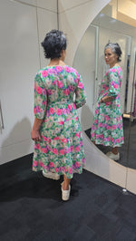 Person wearing a floral dress standing in front of a mirror. Tie Front Dress Green
