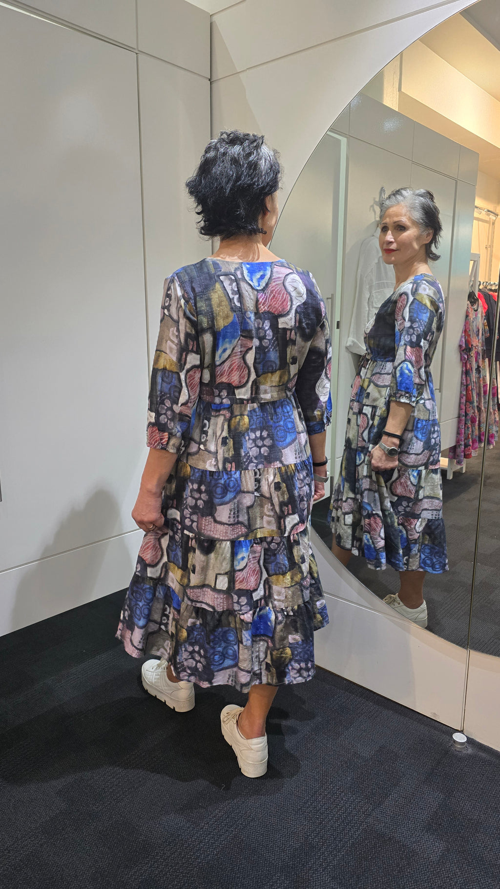 Person wearing a patterned dress standing in front of a mirror. Tie Front Dress Multi