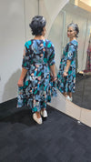 Person wearing a floral dress standing in front of a mirror. Tie Front Dress Blue