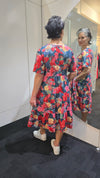 Person wearing a colorful floral dress standing in front of a mirror. Tiered Dress Red
