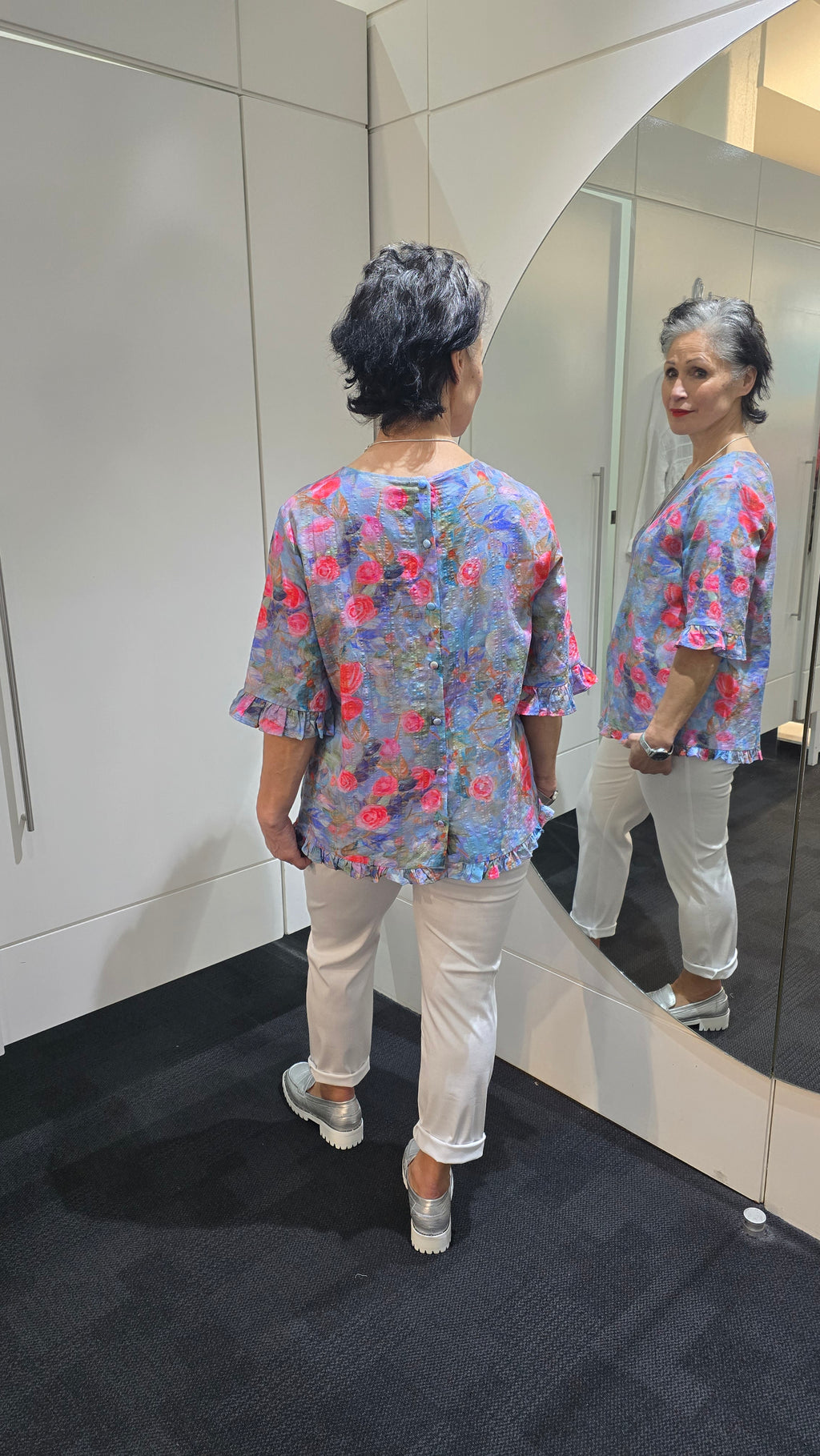Person wearing a floral dress standing in front of a mirror. Round Neck Top Blue