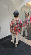 Person wearing a floral dress standing in front of a mirror. Round Neck Top Taupe