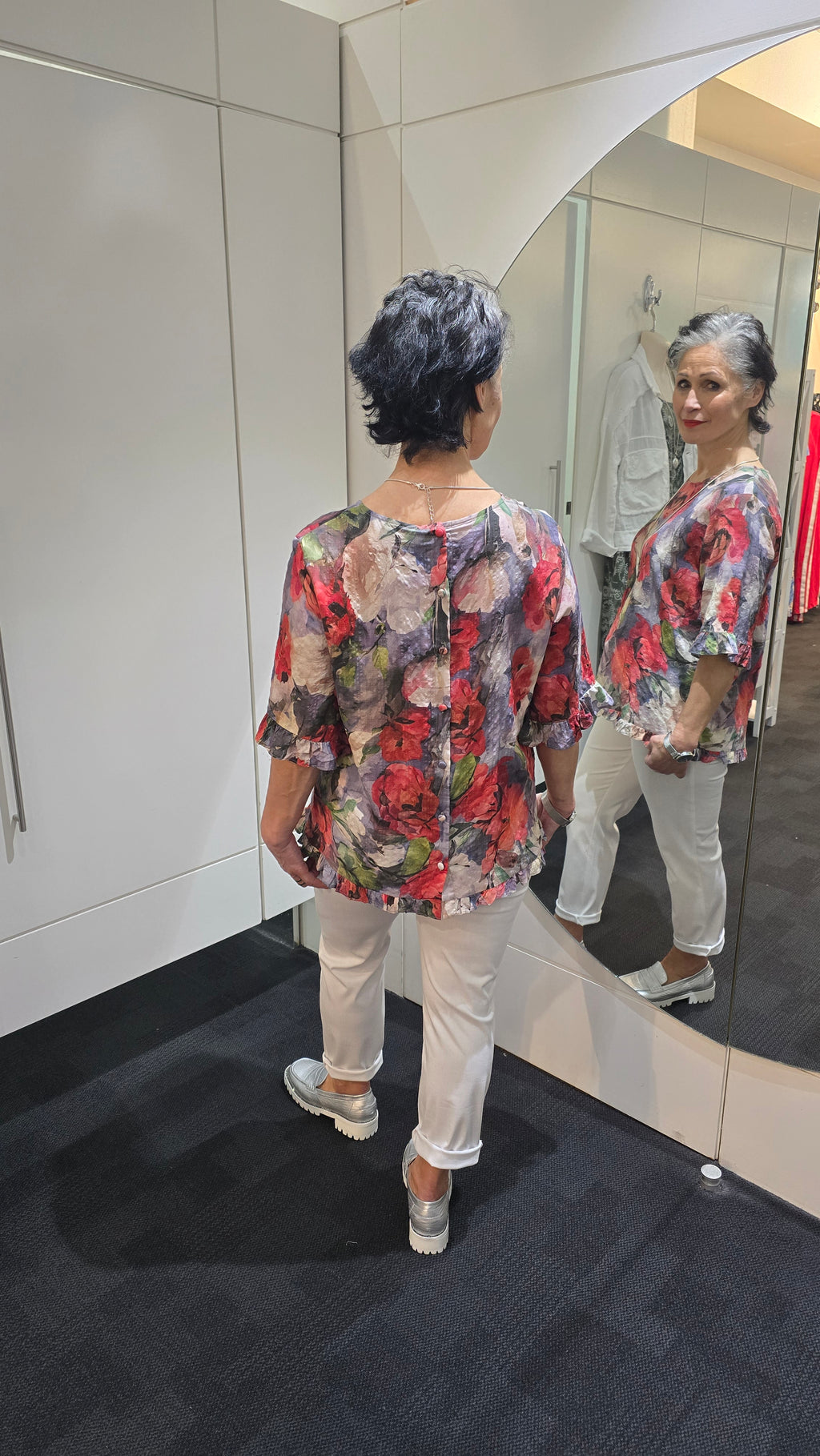 Person wearing a floral dress standing in front of a mirror. Round Neck Top Taupe