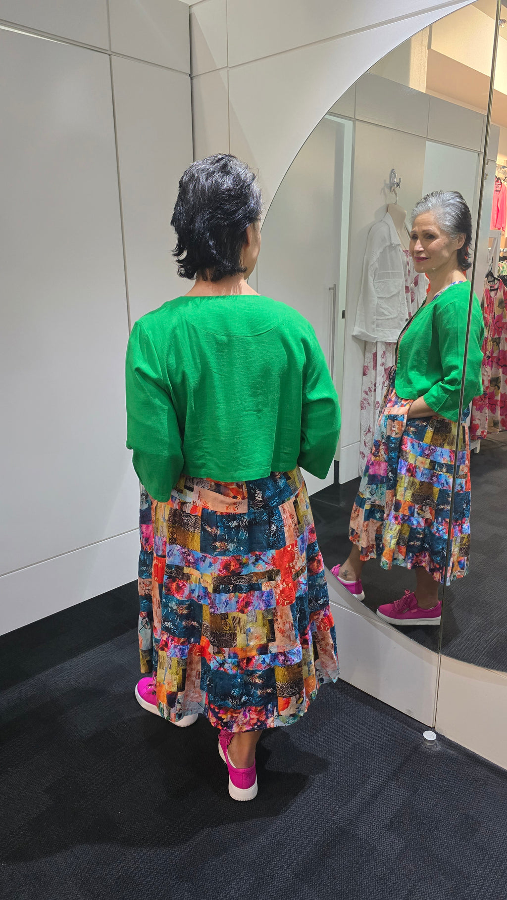 Person wearing a green top and colorful patterned skirt with a blurred background Crop Jacket Green