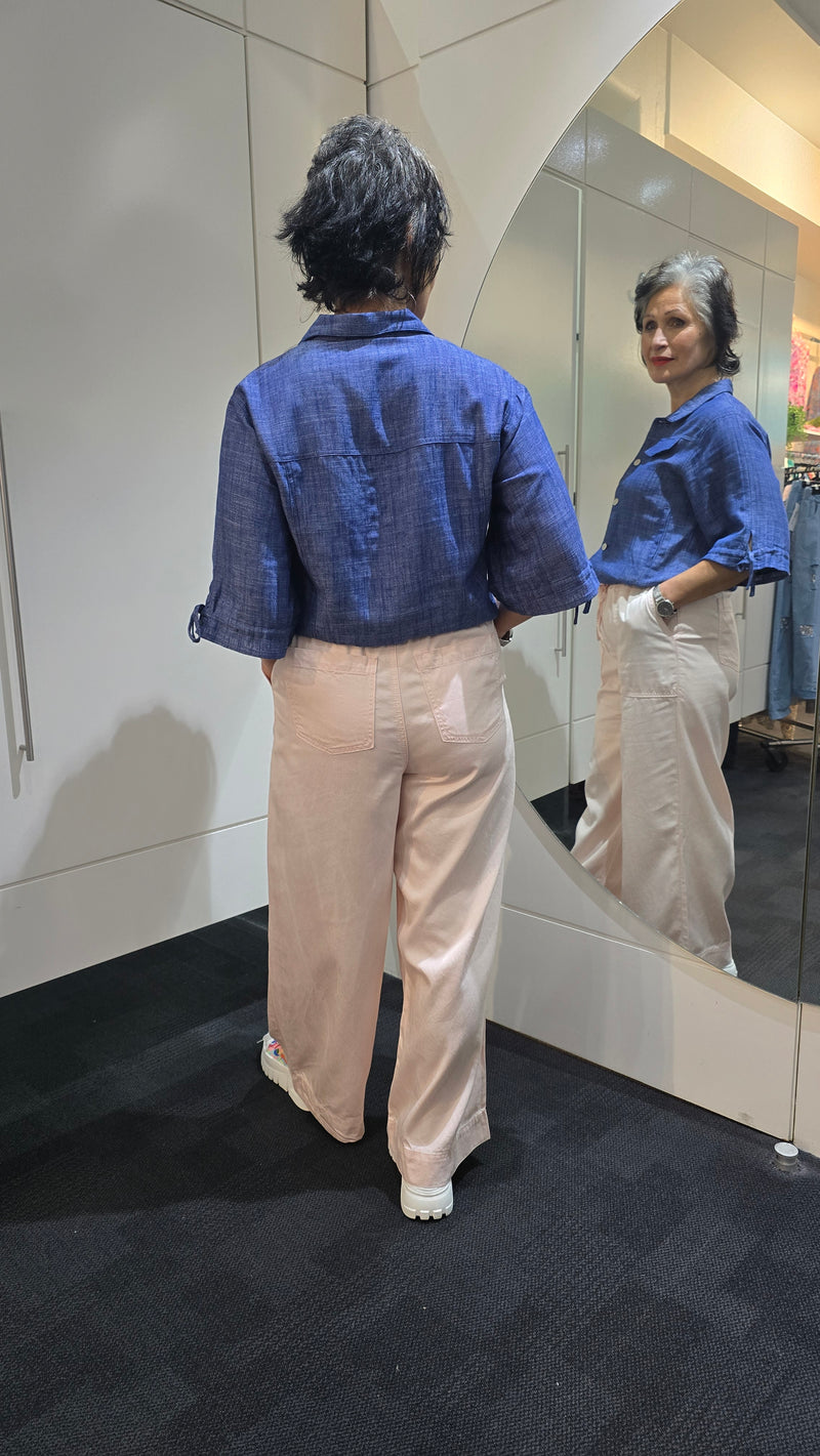 Person wearing a blue jacket and beige pants standing in front of a mirror. Saffra Relax Leg Jean Pink