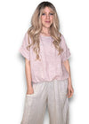 Woman wearing a light pink top and beige pants against a white background Split Back River Tee Baby Pink