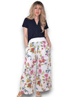 Woman wearing a black top and floral wide-leg pants on a white background Palazzo Doily Rose Pant White