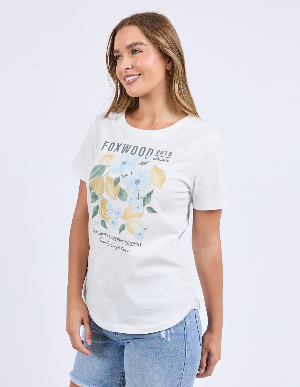 Woman wearing a white t-shirt with floral design and text on a plain background
Limoncello Tee Vintage White