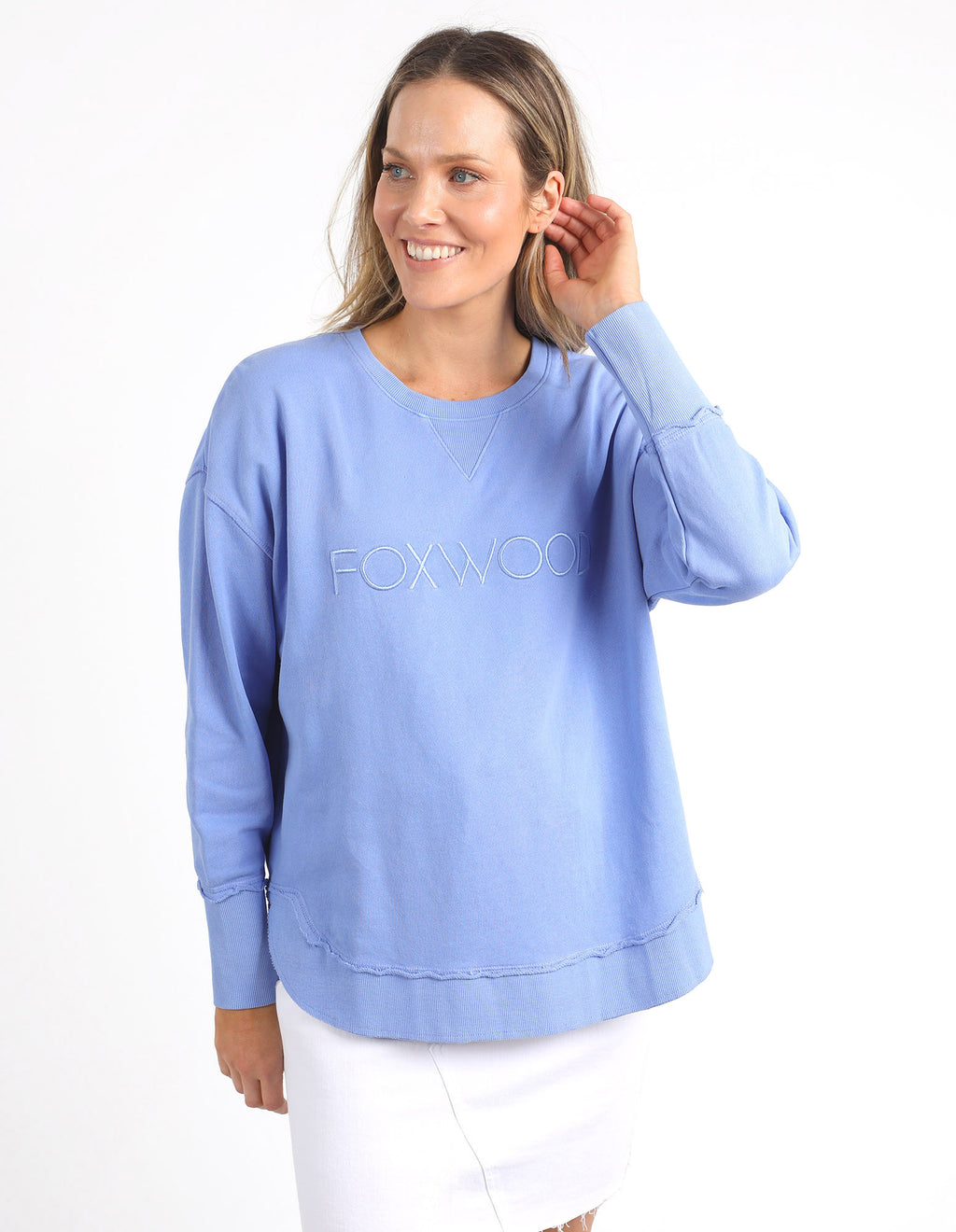 Woman wearing a light blue sweatshirt with 'FOXWOOD' branding on a white background
Simplified Crew Neon Blue