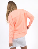Woman wearing a peach-colored sweatshirt and white skirt on a white background
Simplified Crew Neon Peach
