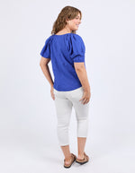 Woman wearing a blue top and white pants on a white background
The Grove Top Ocean Blue