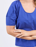Person wearing a blue shirt with arms crossed on a light gray background
The Grove Top Ocean Blue