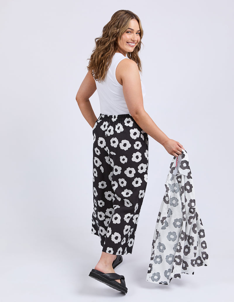 Woman wearing a white sleeveless top and black floral pants, holding a matching top.
Azalea Pants Navy