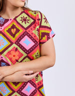 Person wearing a colorful patterned shirt with geometric designs on a light gray background
Rhode Dress Geo Print