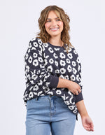 Woman wearing a navy sweater with white floral pattern and light blue jeans on a white background
Azalea Crew Navy