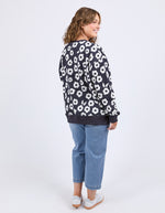 Woman wearing a navy sweater with white floral pattern and blue jeans on a white background
Azalea Crew Navy