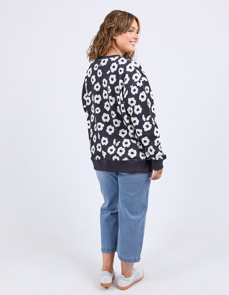 Woman wearing a navy sweater with white floral pattern and blue jeans on a white background
Azalea Crew Navy