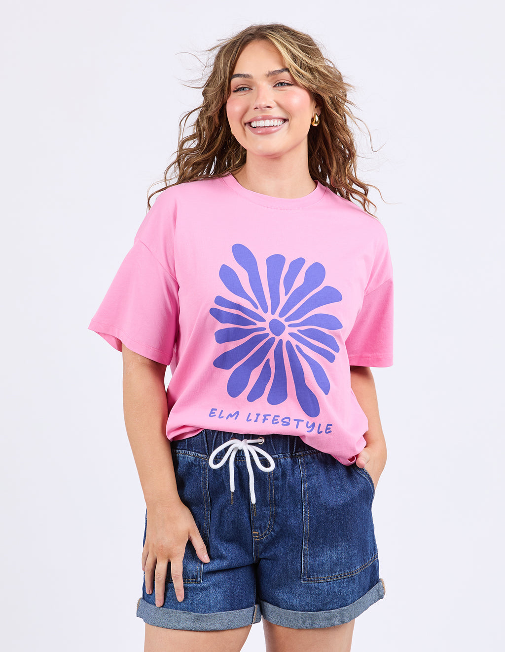 Woman wearing a pink t-shirt with a blue floral design and denim shorts on a white background
Camelia Tee Chateau Rose