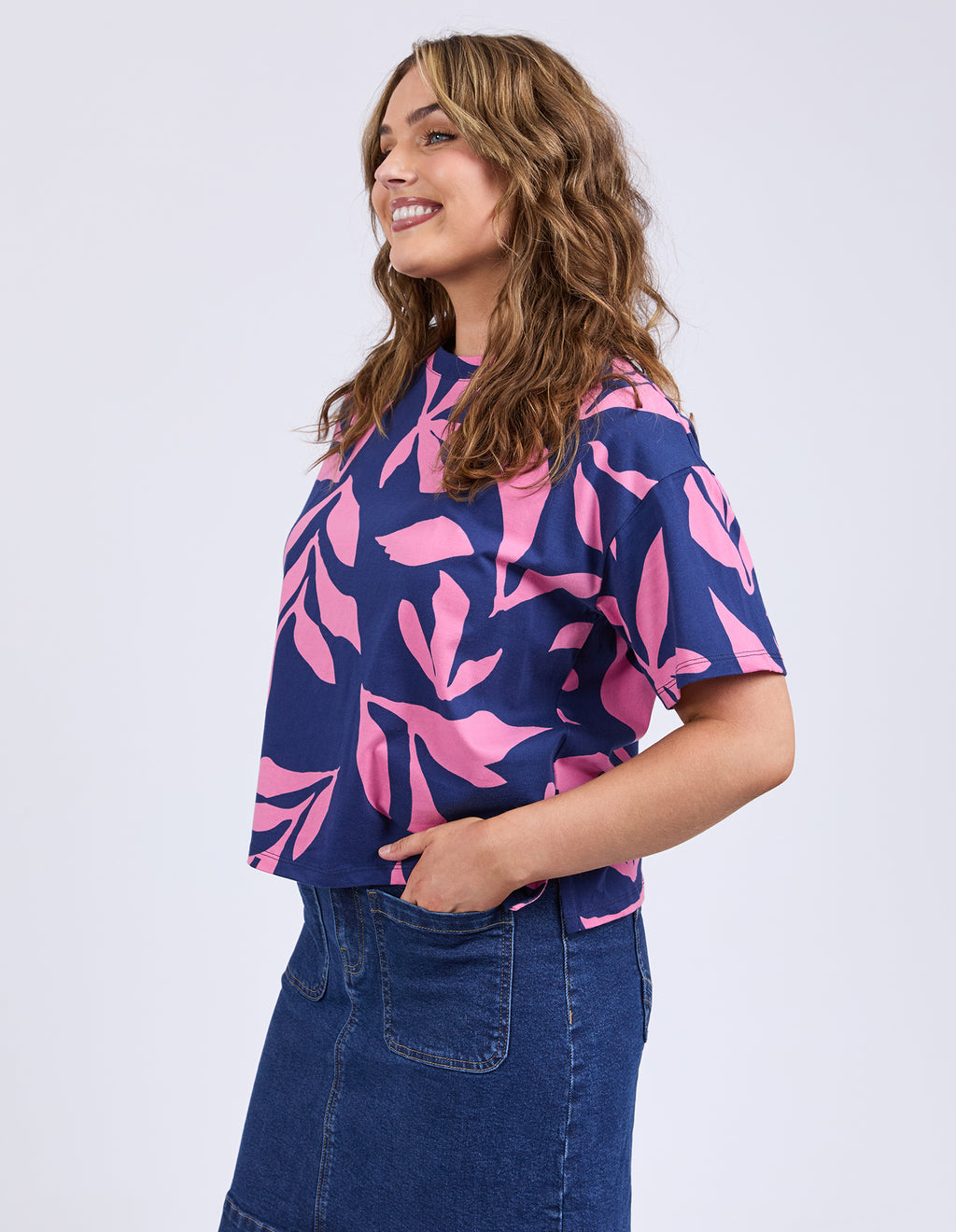 Woman wearing a navy blue t-shirt with pink leaf pattern and blue jeans on a white background
Mimosa Tee Blue Depths