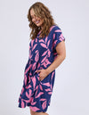 Woman wearing a navy dress with pink leaf pattern on a white background
Mimosa Dress Blue Depths