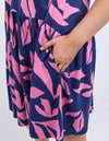 Navy blue dress with pink leaf pattern worn by a person on a white 
background
Mimosa Dress Blue Depths