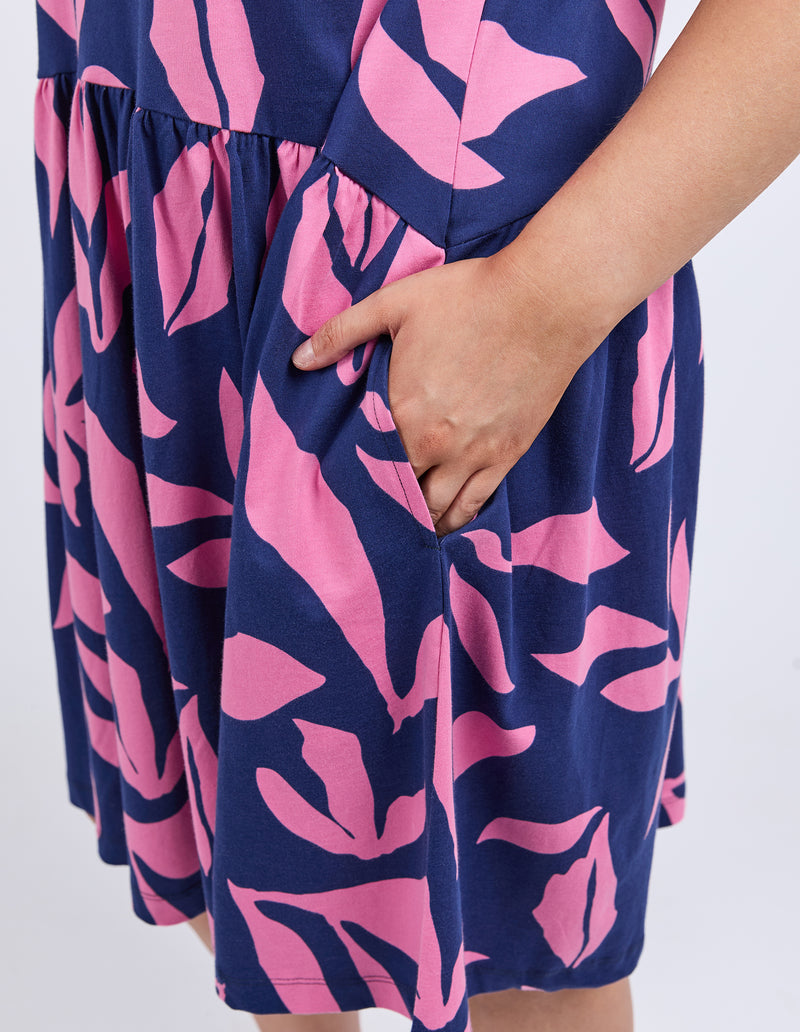 Navy blue dress with pink leaf pattern worn by a person on a white 
background
Mimosa Dress Blue Depths