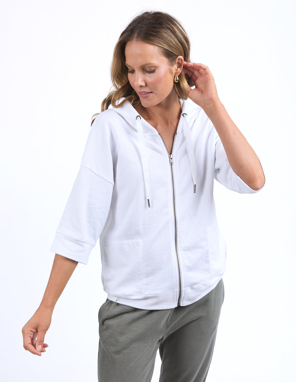 Woman wearing a white zip-up hoodie and gray pants on a white background
Beachy Zip Hoodie White