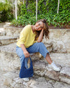 Woman sitting on stone steps outdoors holding a blue bag
Mazie Vee Neck Top Lemon