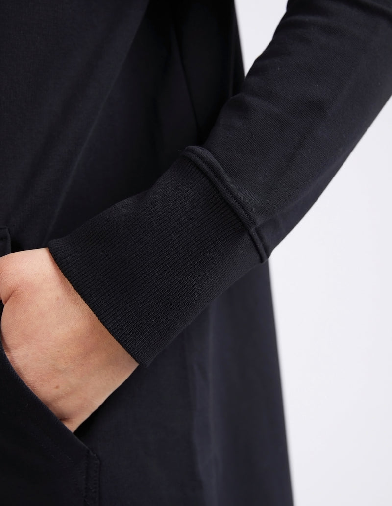 Close-up of a person wearing a black long-sleeve shirt with a blurred background
Mara Zip Hoodie Black