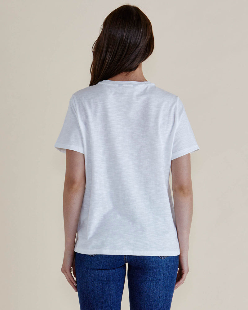 Person wearing a plain white t-shirt and blue jeans on a beige background
