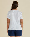 Woman wearing a white t-shirt with a pineapple graphic and 'Paradise' text on a beige background Ellia Crew Tee White