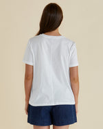 Woman wearing a white t-shirt with a pineapple graphic and 'Paradise' text on a beige background Ellia Crew Tee White