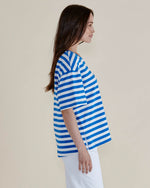 Woman wearing a blue and white striped shirt against a beige background